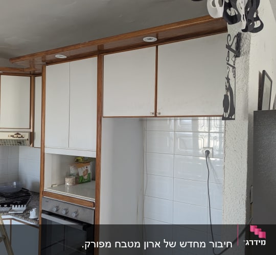 מטבח עם ארונות לבנים ותנור אפייה